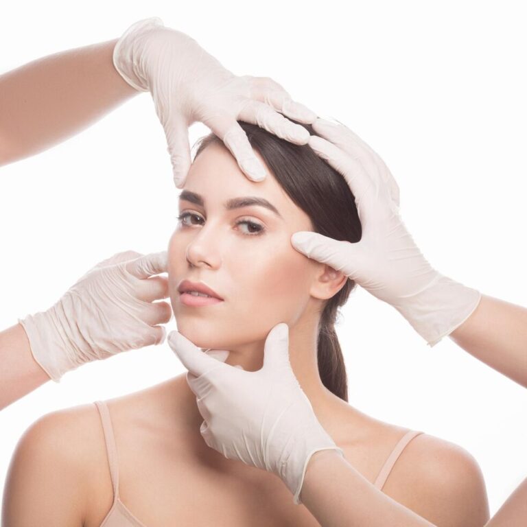 handmade-beauty-beautiful-young-woman-keeping-eyes-opened-while-four-hands-medical-gloves-touching-her-face-isolated-white-background_549566-807